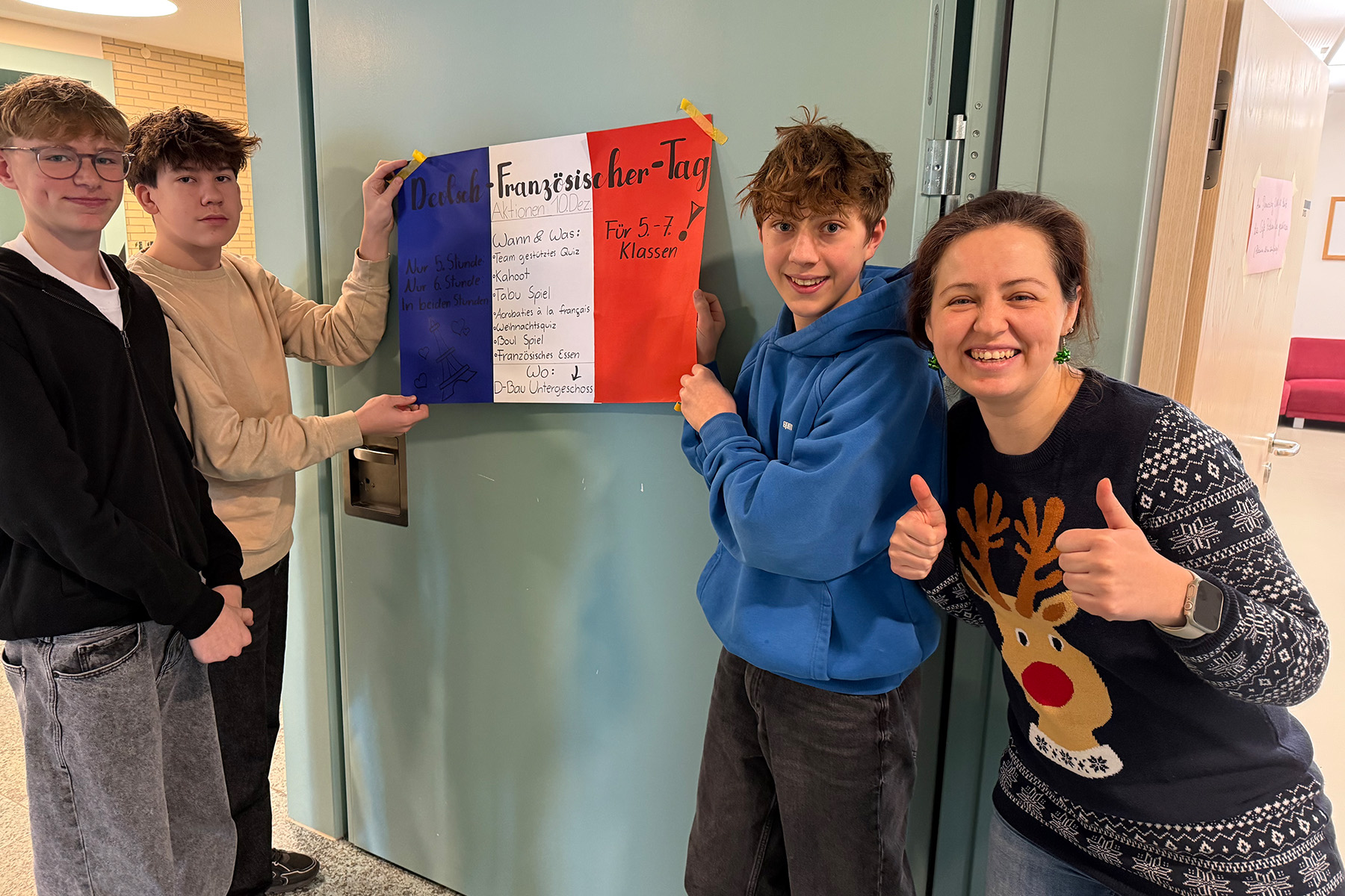 Drei Schüler halten die französische Flagge, die Lehrerin macht die Daumen nach oben