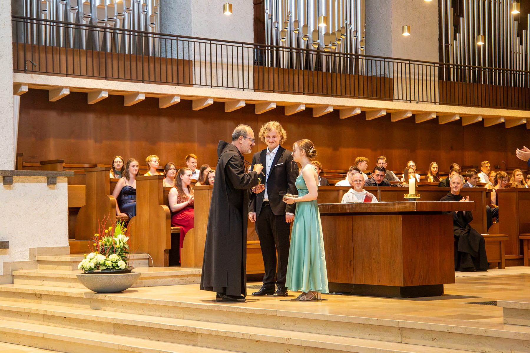 Der Abt überreicht der Schülerin und dem Schüler die Auszeichnung in der Abteikirche