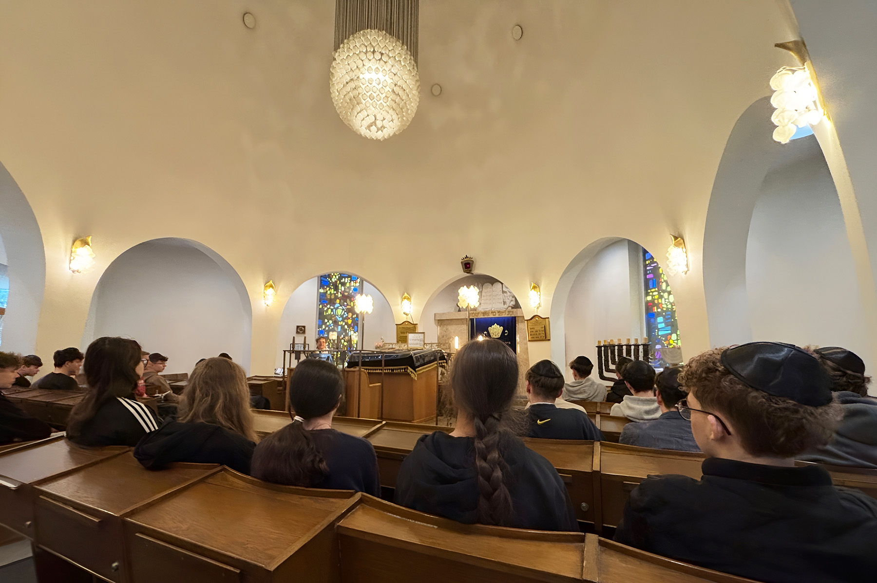 Schülerinnen und Schüler sitzen in einem Raum der Synagoge
