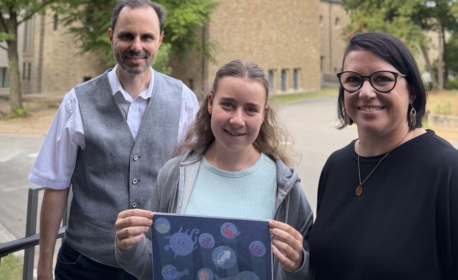 Mann und Frau stehen bei einem Mädchen, das ein Bild hochhält