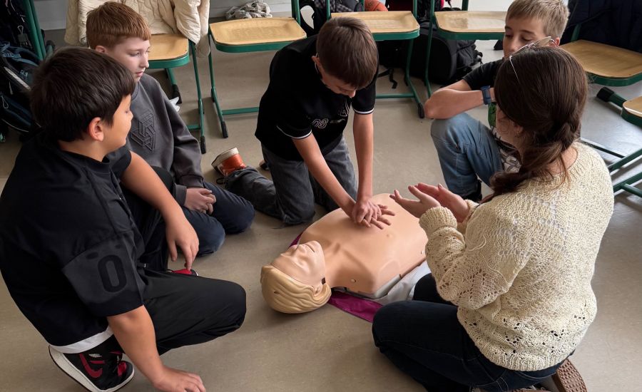 Eine Gruppe von Schülern übt an der Puppe die Herzmassage