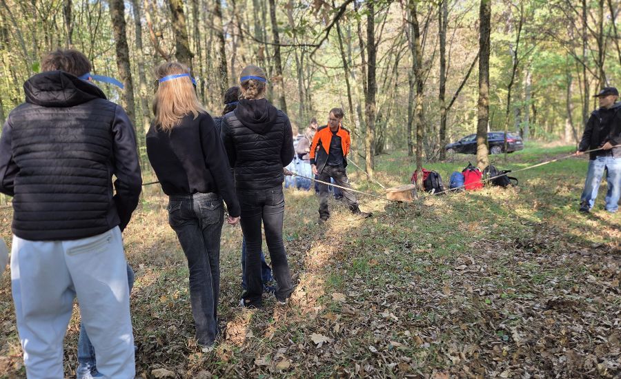 Schülerinnen und Schüler mit Schutzmasken transportieren eine Baumscheibe im Wald