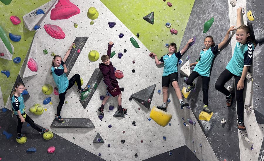 Sechs Schülerinnen und Schüler an einer bunten Kletterwand